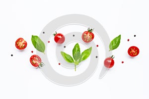 Fresh  cherry tomatoes with basil leaves and different type of peppercorns on white background.