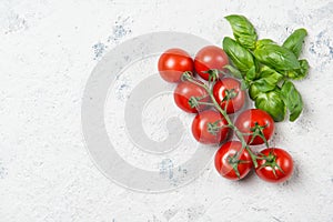 Fresh cherry tomatoes with basil leaves on a stone table, top view with copy space