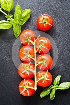 Fresh cherry tomatoes on a black background with spices. Top vie