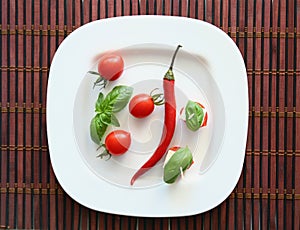 Fresh cherry tomatoes and chili on white.