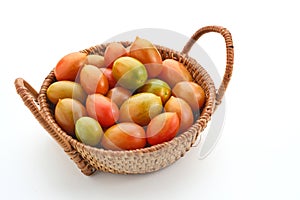 Fresh cherry tomatoes in the rattan basket isolated on white background.