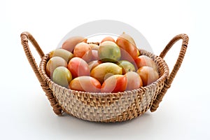 Fresh cherry tomatoes in the rattan basket isolated on white background.