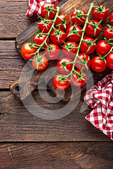 Fresh cherry tomatoes on twigs on wooden table