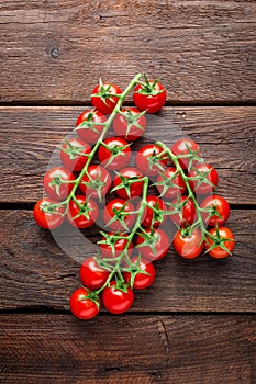Fresh cherry tomatoes on twigs on wooden table