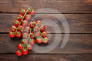 Fresh cherry tomatoes on twigs on wooden table