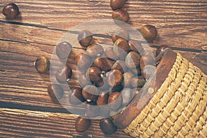 Fresh chestnuts in the basket falling on a brown wooden table