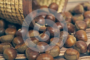 Fresh chestnuts in the basket falling on a brown wooden table