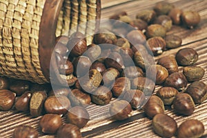 Fresh chestnuts in the basket falling on a brown wooden table