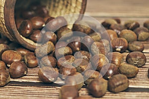 Fresh chestnuts in the basket falling on a brown wooden table