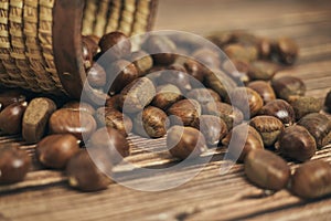 Fresh chestnuts in the basket falling on a brown wooden table