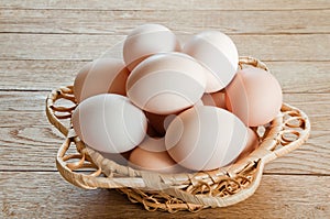 Fresh chicken eggs in wicker basket on wooden table