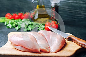 Fresh chicken fillet with vegetables, spices and herbs on a wooden cutting board, meat ingredient for cooking