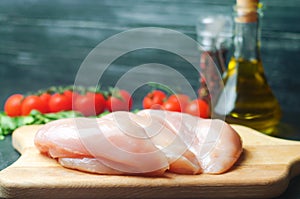 Fresh chicken fillet with vegetables, spices and herbs on a wooden cutting board, meat ingredient for cooking