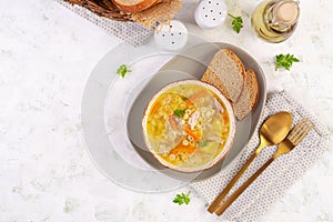 Fresh chicken soup with vegetables and stelline pasta in a bowl with carrot and parsley.