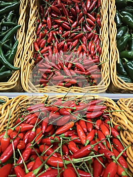Fresh chillies variety piled in the baskets on the market. Birdseye chillies with some Green Cayenne and Jalapeno peppers on sides