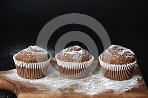 Fresh chocolate muffins on a wooden board
