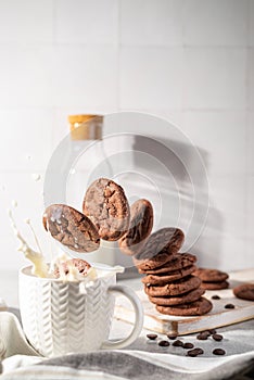 Fresh chocolate ship cookies making splash in a cup of milk