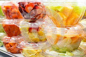 Fresh chopped fruits in plastic boxes in local store in USA. In-house cut and packed strawberries, blueberries, grapes