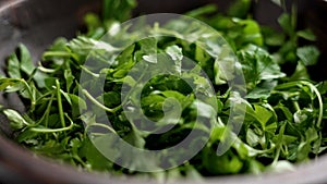 Fresh chopped green parsley leaves falling into a wooden rustic bowl.