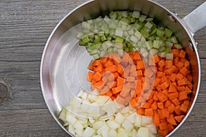 Fresh chopped onions, carrots and celery in a stainless steel pan, ingredients for sauteed