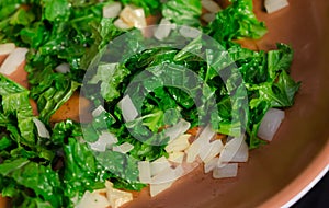 Fresh chopped organic super food Kale leaf and onion being sauteed.