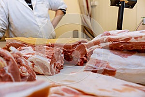 Fresh chopped pieces of meat and male hands of cutting meat pork on table