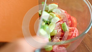 Fresh chopped tomatoes and cucumbers in a glass bowl on a wooden table