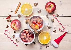 Fresh Christmas drink mulled wine, apple, orange, cinnamon and cloves, next spread ingredients, candy, decorations for New Yea