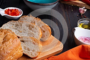 Fresh ciabatta bread  with blue bowl and ingredients served at dark wooden table. meditarranean cuisine. close up photo