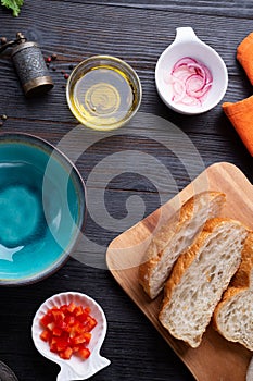 Fresh ciabatta bread  with blue bowl and ingredients served at dark wooden table. meditarranean cuisine. flat lay photo