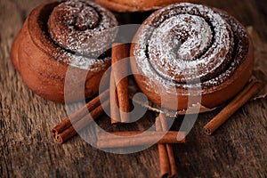 Fresh cinnamon buns on wooden background. Sweet cinnamon rolls.