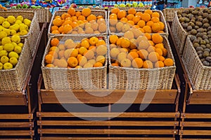 Fresh citrus fruits in baskets on a store shelf.