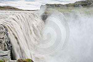 Fresh clean Dettifoss waterfall in Iceland in summer with loads of water flowing and mist,