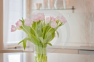 A fresh and clean home office with soft pink tulip flowers in a kitchen for Women`s Day celebration. Airy Scandinavian/Nordic