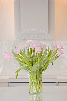 A fresh and clean home office with soft pink tulip flowers in a kitchen for Women`s Day celebration. Airy Scandinavian/Nordic