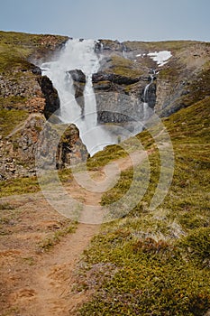 Fresh clean small waterfall in Iceland in summer with loads of water flowing between rocks and unrecognisable person