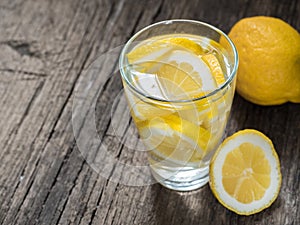 Fresh clean water in a glass with slices of lemon. Lemonade on wooden table. Living water, healthy drink
