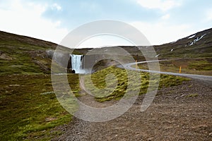 Fresh clean waterfall Gufufoss near Seydisfjordur in Iceland in summer with loads of water and curvy road, snow