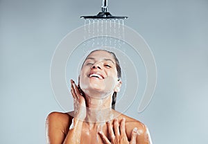 So fresh and so clean. a young woman taking a shower against a grey background.