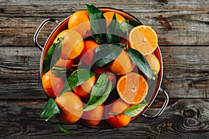 Fresh Clementine Mandarin Oranges fruits or Tangerines with leaves on wooden background