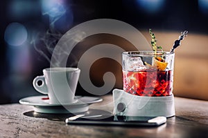 Fresh cocktail drink with cup of coffee and smartphone. Alcoholic, non-alcoholic drink-beverage at the bar counter in the pub. photo