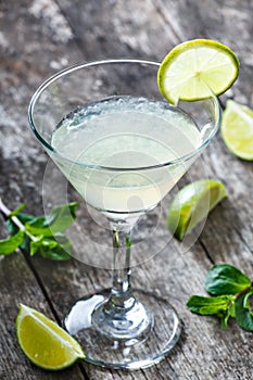 Fresh cocktail with mint and lime in glass on wooden background. Summer drinks and alcoholic cocktails