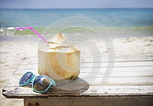 Fresh coconut cocktail and sunglasses on tropical beach