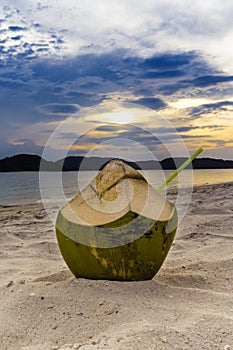 Fresh coconut cocktails on sandy tropical beach at sunset time