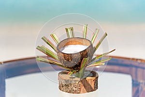 Fresh coconut juice in designed cup on the glass table at the beach with ocean