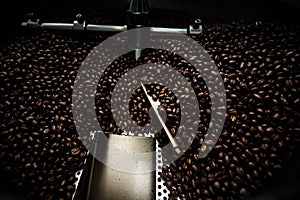 Fresh coffee beans and roasted spinning cover professional machine close up photo blur and dark background  long exposure shot