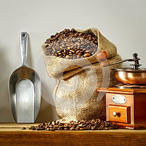 Fresh coffee in jute sack on wooden shelf with empty copy space for your products and decoration. Light gray wall background.