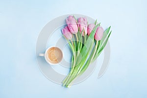 Fresh coffee and pink tulip flowers on pastel background top view. Beautiful spring breakfast on Mothers or Womans day. Flat lay.