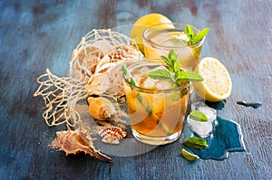Fresh cold iced tea with mint, ice, lemons and sea shells, refr