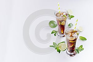 Fresh cold summer drink of cola, ice, lime, leaf mint on soft light white background, copy space, top view.